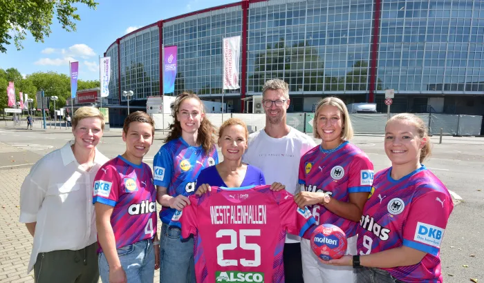 Spielerinnen der Nationalmannschaft, Bundestrainer Markus Gaugisch, Clara Woltering und Sabine Loos posieren vor der Westfalenhalle mit Trikot.