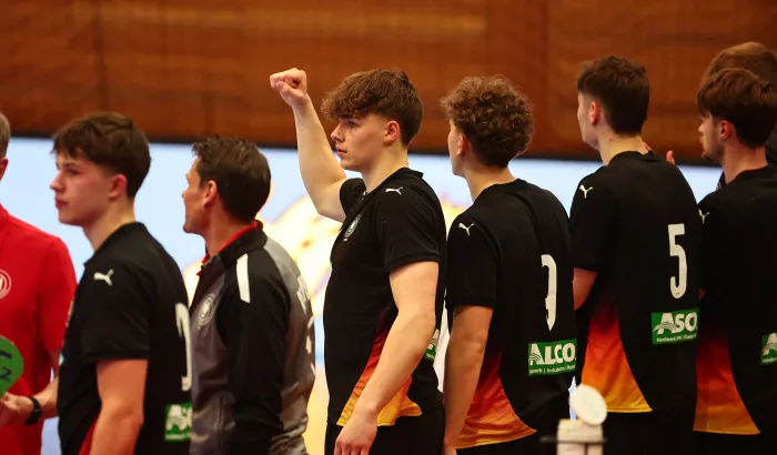Eine Truppe Männer die in einer Handballhalle stehen und jubeln 