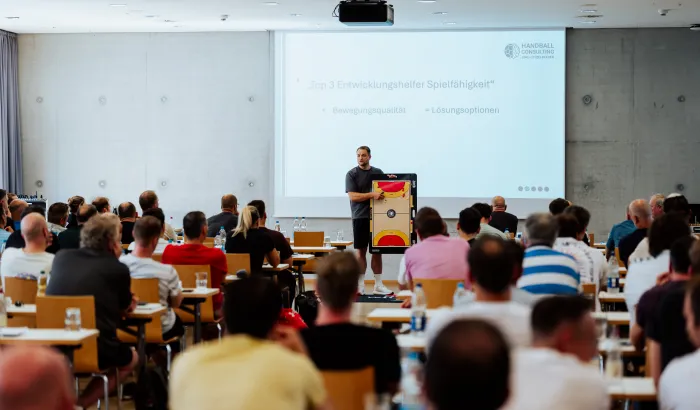 Eine Versammlung von Menschen die sich einen Vortrag anhören.