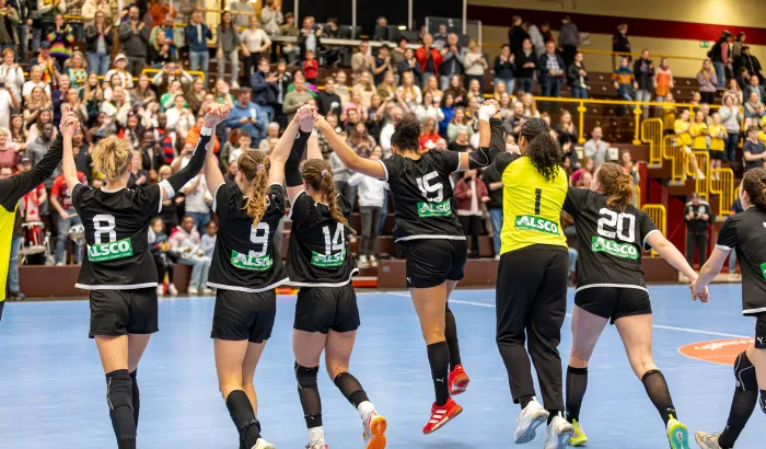 Eine Truppe jubelnder Spielerinnen die ihre Hände in die Luft strecken