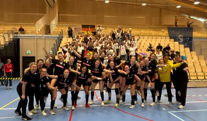 Eine Truppe von Mädels in Hnandballsachen, die zusammenstehen mit den armen ineinander verschlungen.. 