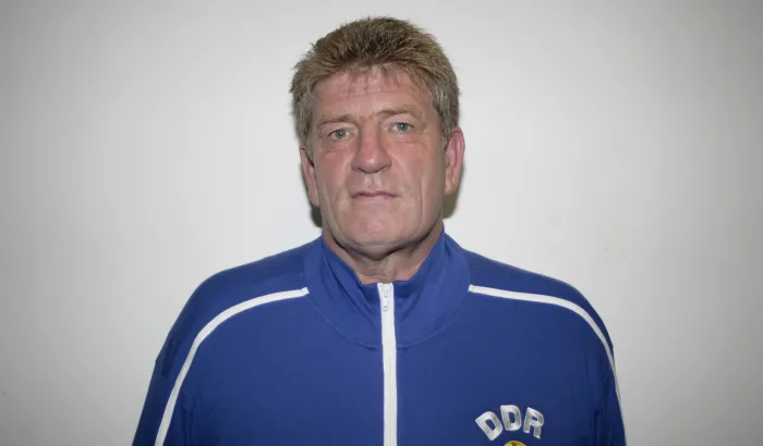 Ein Porträtfoto eines Mannes in blauer Jacke mit DDR auf der Brust