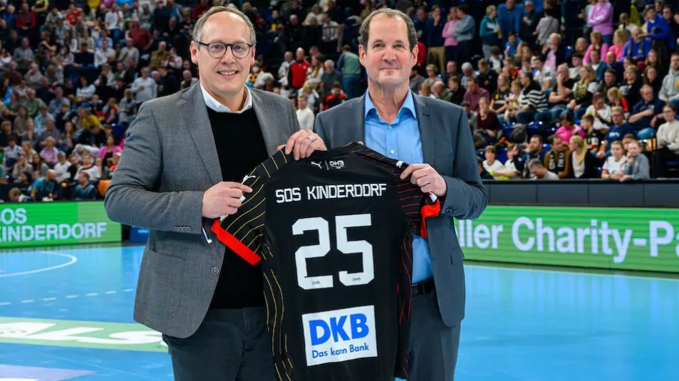 Mark Schober und Georg Falterbaum präsentieren ein DHB Trikot auf dem Handballfeld