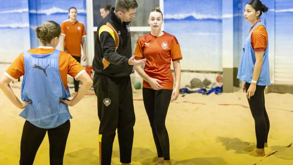 Beachhandballtrainer tauscht sich mit einer Spielerin aus