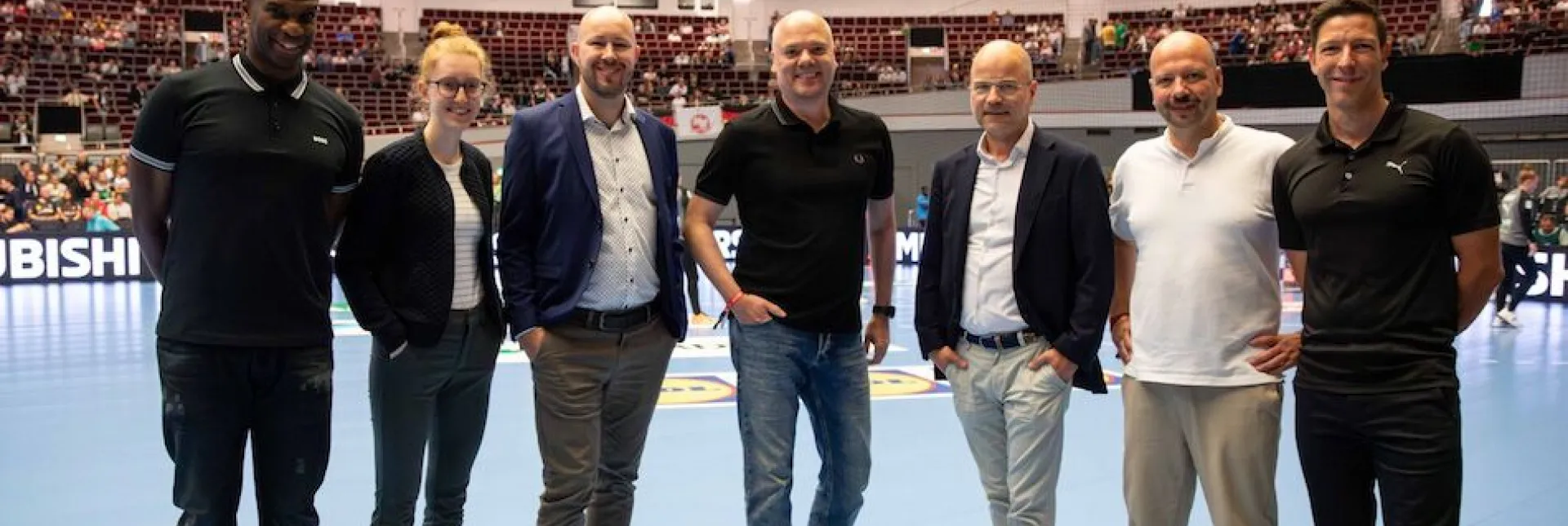 Die Verantwortlichen von Adesso und DHB gemeinsam auf dem Handballfeld. 