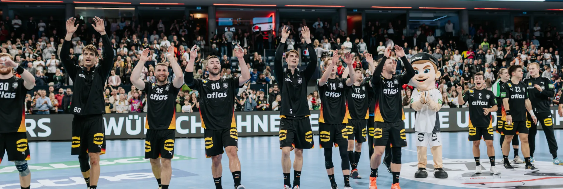 Handball-Männer-Nationalmannschaft jubelt nach Spiel zu Fans.