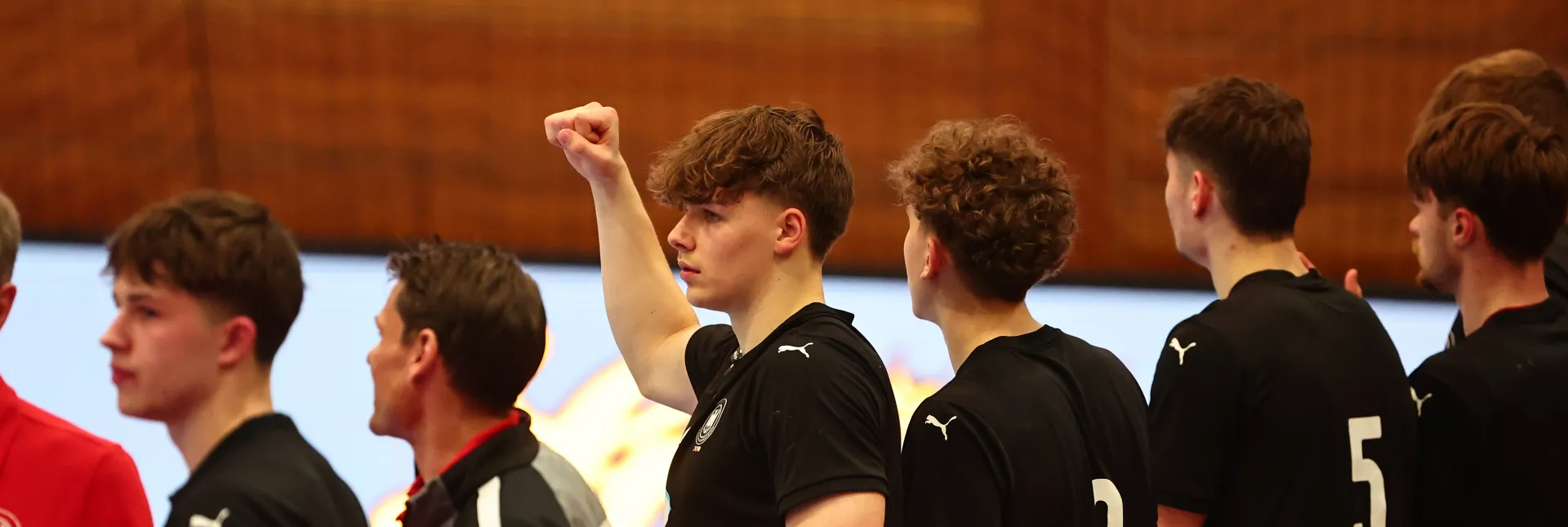 Eine Truppe Männer die in einer Handballhalle stehen und jubeln 