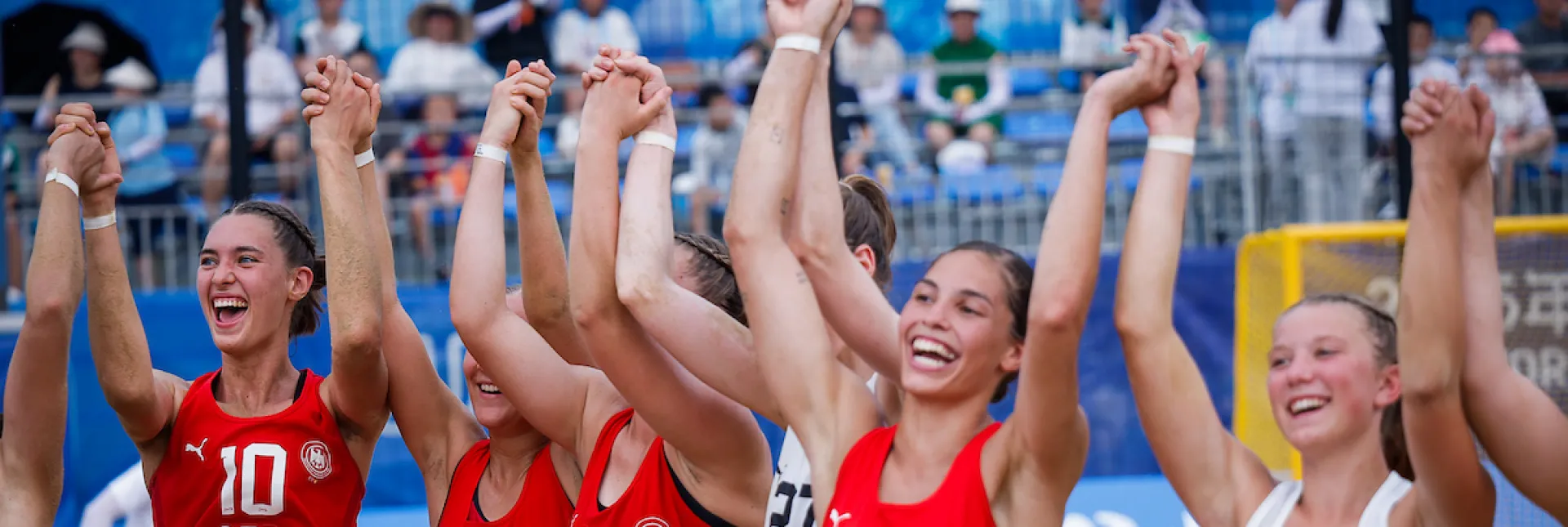 Eine Gruppe von jungen Frauen in roten Oberteilen jubeln zusammen