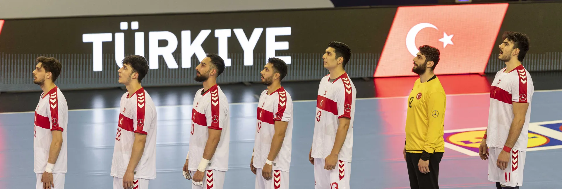 Türkische Handball-Nationalmannschaft singt die Hymne vor einem Handballspiel.