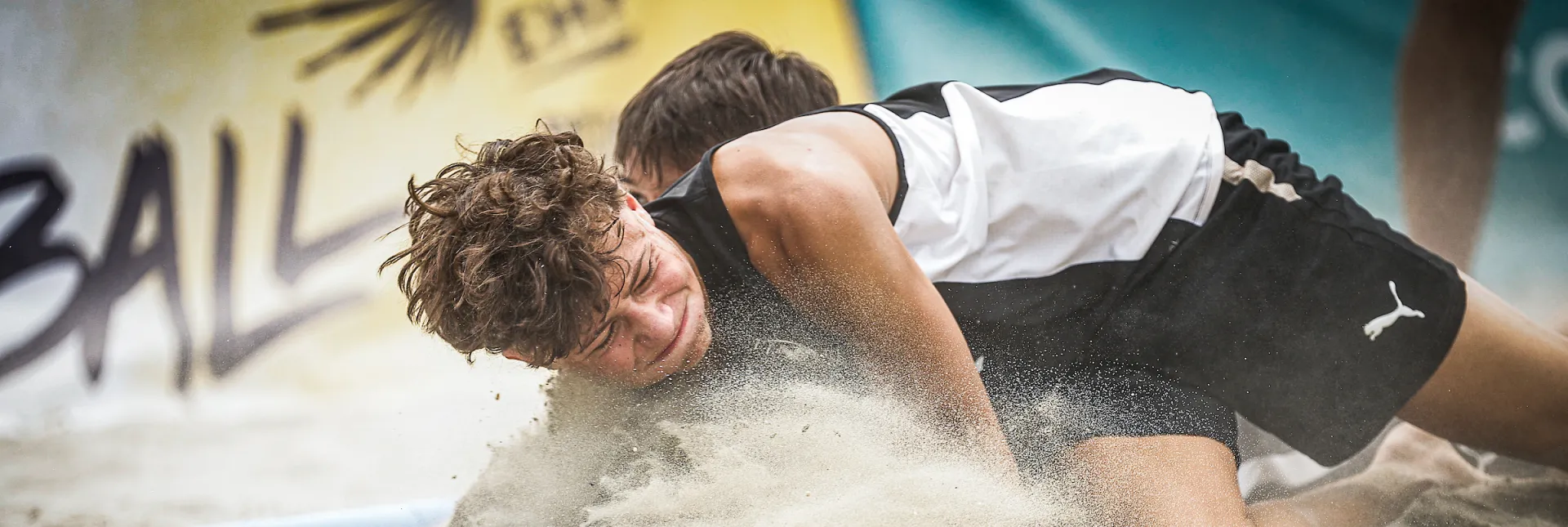 Zwei Spieler kämpfen im Sand um den Ball.