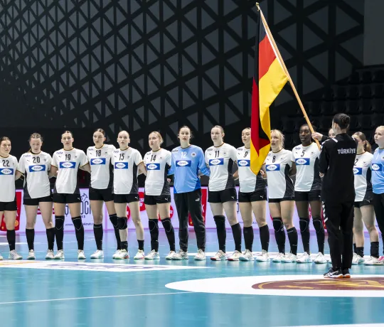 Eine Truppe von jungen frau steht in einer Reihe und schaut die Deutschlandflagge an