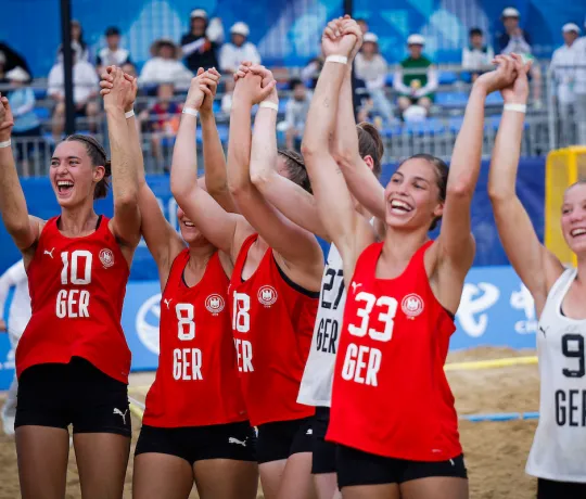 Eine Gruppe von jungen Frauen in roten Oberteilen jubeln zusammen