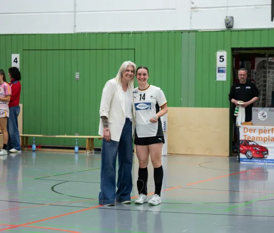 Zwei Frauen die in die Kamera lächeln und einen Pokal in den Händen halten