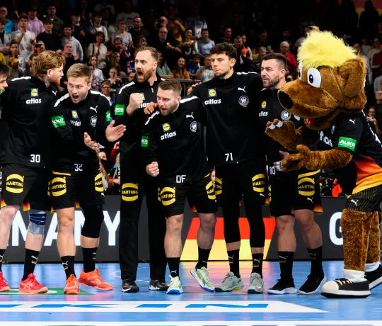 Deutsche Handball-Männer-Nationalmannschaft steht zusammen in einer Reihe und jubelt sich zu.