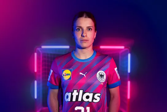 Nationalspielerin Alexia Hauf im magentafarbenen Sondertrikot vor einem mit LED-Stangen beleuchteten Tor.