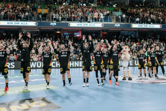 Handball-Männer-Nationalmannschaft jubelt nach Spiel zu Fans.