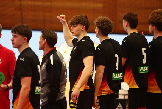 Eine Truppe Männer die in einer Handballhalle stehen und jubeln 