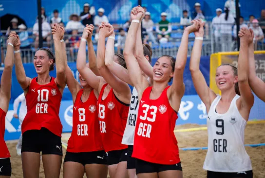Eine Gruppe von jungen Frauen in roten Oberteilen jubeln zusammen