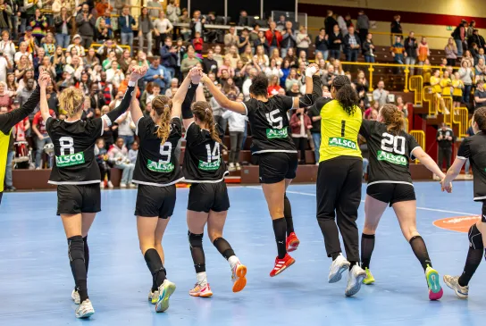 Eine Truppe jubelnder Spielerinnen die ihre Hände in die Luft strecken