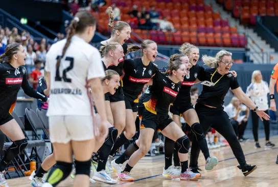 Eine Handballmannschaft die sich freut und zusammen jubelt.